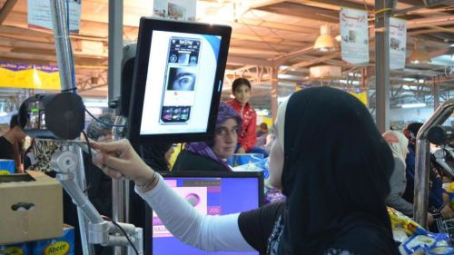 A Syrian refugee uses WFP’s Building Blocks blockchain enabled digital cash to pay for groceries at a local market in Zaatari refugee camp in Jordan
