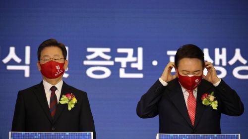 Yoon Suk-yeol and Lee Jae-myung stand at podiums in front of a blue screen.