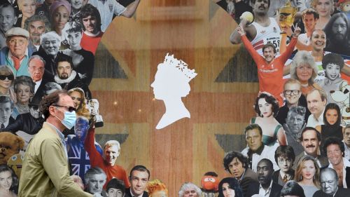 A man wearing a protective face mask walks past a window display ahead of the Platinum Jubilee celebrations for Britain's Queen Elizabeth