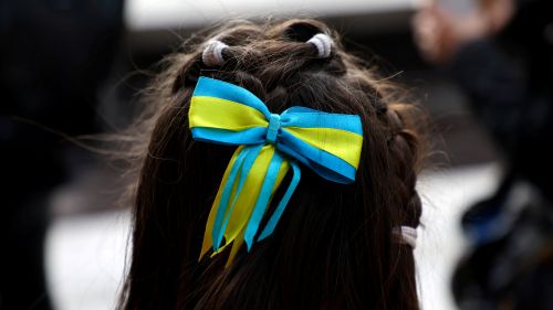 Julija, 10, fleeing from Kyiv wears a hair bow in the colours of the Ukrainian national flag as she waits with her relatives on a platform for a train