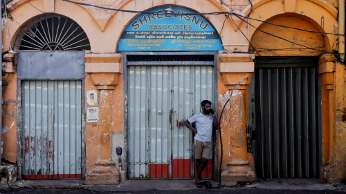 A worker uses a mobile phone in front of a closed essential food store during a nationwide strike demanding the resignation of President Gotabaya Rajapaksa and his cabinet, amid the country's economic crisis, in Colombo, Sri Lanka, April 28, 2022.