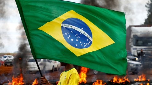 A man holds a Brazilian flag as supporters of Brazil's President Jair Bolsonaro block a highway during a protest against President-elect Luiz Inacio Lula da Silva