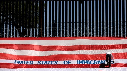 A man writes United States of Immigrants on a flag