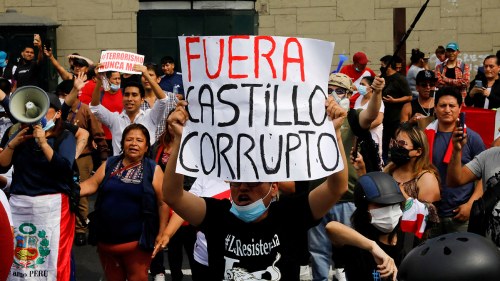 People hold signs while protesting against Peru's President Pedro Castillo after Congress approved his removal from office