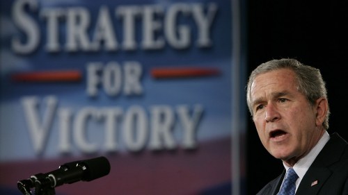 George W. Bush speaks in front of a sign that says 'strategy for victory'
