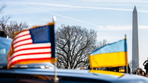 A US flag and Ukrainian flag fly on a car
