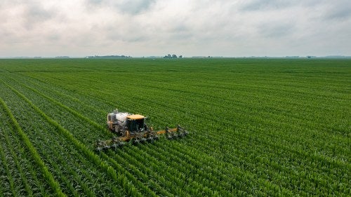 A tractor plows a green field.