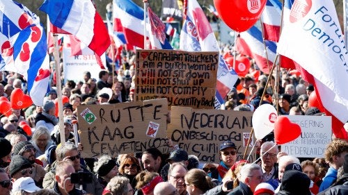 Dutch farmers holding banners and flags protest government policies to limit nitrogen emissions in The Hague, Netherlands.