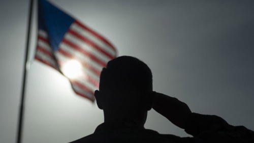 a soldier salutes the American flag