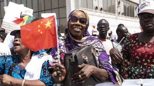 A Senagalese person waves a Chinese flag