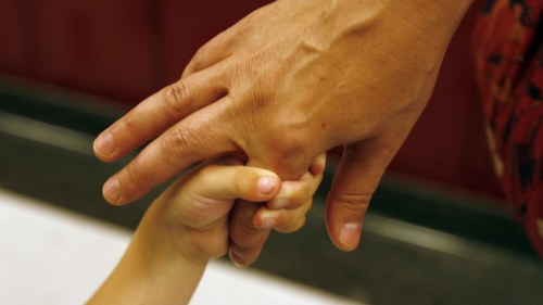 Young Chicago Public Schools student's hand holding a parent's finger