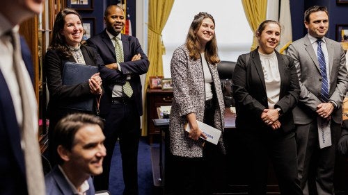 A group of people stand in an office smiling