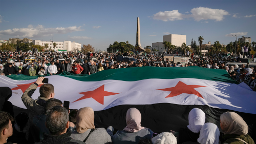 Syrians display a giant "revolutionary" Syrian flag during a celebratory demonstration following the first Friday prayers since Bashar Assad's ouster, in Damascus' central square, Syria, on Friday, Dec. 13, 2024.