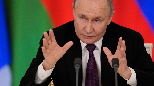 Russian President Vladimir Putin holds his hands up and speaks into a microphone during a news conference on March 13, 2025.