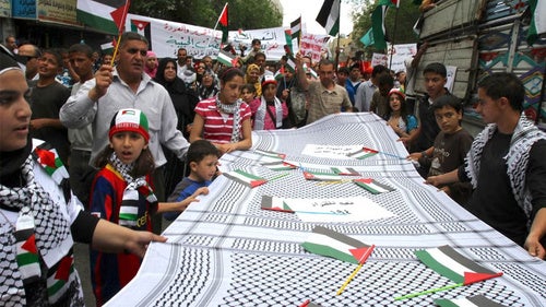 Jordanian children hold a huge kefiyah, a traditional Palestinian scarf.