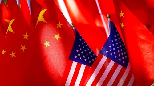 Two miniature American flags rest in front of a larger group of Chinese flags.