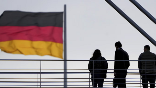Silhouettes of three people against a gray sky with the German flag in the foreground