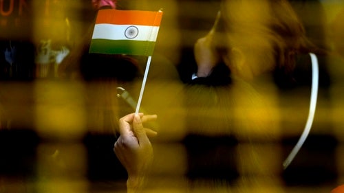 A woman waves a handheld Indian flag.