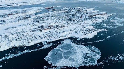 Houses covered by snow are seen on the coast of Greenland