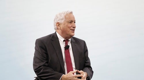 Walter Isaacson speaking in red tie, in front of light grey background