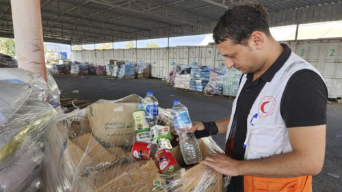 United Nations and Red Crescent workers prepare the aid for distribution to Palestinians at UNRWA warehouse in Deir Al-Balah, Gaza Strip