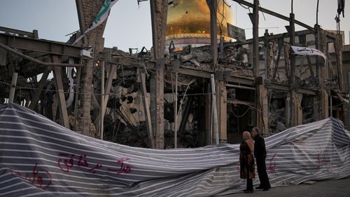 Pedestrians look at a destroyed building in Zanjan, Iran