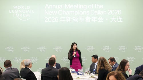 A woman speaks into a microphone in front of an audience