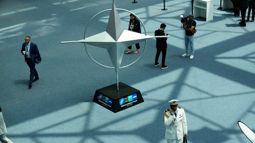 Participants walk near displays during the NATO Defense Industry Forum