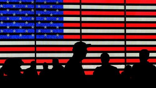 Silhouettes against a backdrop of the American flag