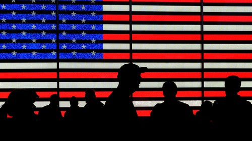 Silhouettes against a backdrop of the American flag