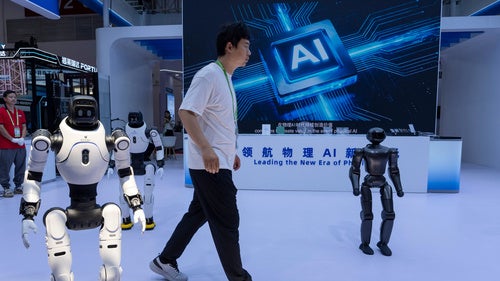 A person passes by a display of robots and a sign that says AI