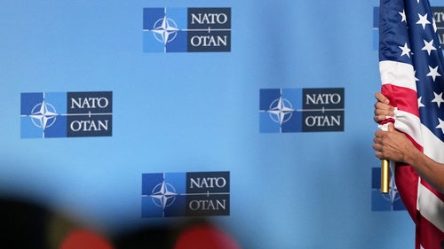 A person carries the US flag onto the podium prior to a media statement from NATO Secretary General Mark Rutte