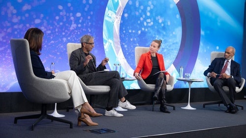 Speakers sitting on stage with a blue backdrop.