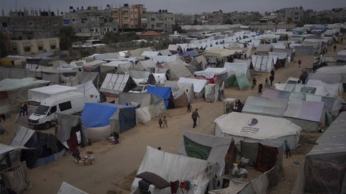 Palestinians displaced by the Israeli ground offensive on the Gaza Strip walk at the makeshift tent camp in Rafah