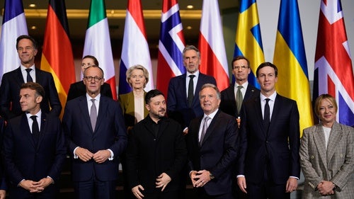 World leaders stand in front of a group of national flags