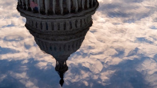 The US Capitol building pictured in the reflection on water