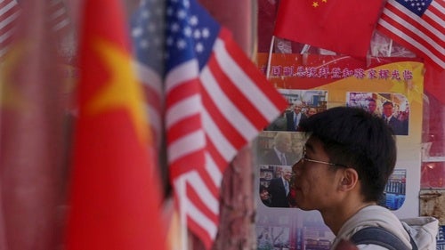 A man walks into a merchandise store displaying Chinese and United States' national flags