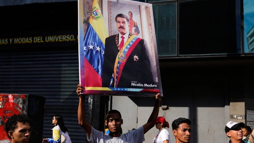 A government supporter holds a banner with a photo of President Nicolas Maduro during a protest demanding his release from U.S. custody in Caracas, Venezuela.