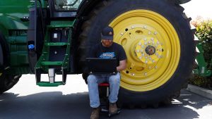 A farmer uses a computer on his tractor. 