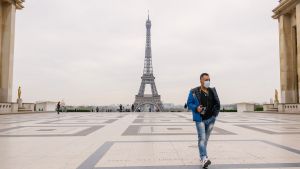 Paris coronavirus. Man wearing a mask walking in front of the Eiffel Tower on the first day of Paris lock-down.