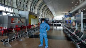 A man in PPE stands in an empty airport