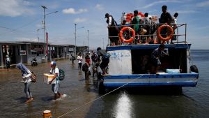 Passengers of a boat walk through rising sea water during high tide at Kali Adem port in Jakarta, Indonesia.