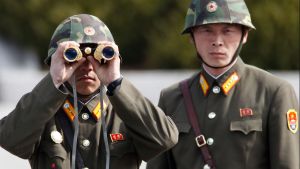 North Korean soldiers look to the South through binoculars while on patrol.