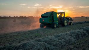 A farmer rides a tractor through a crop while harvesting