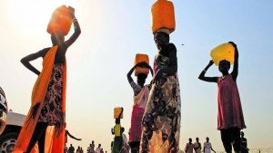 South Sudanese carry water containers on their heads