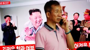 A man stands near a TV showing a file picture of North Korean leader Kim Jong Un for a news report on North Korea firing short-range ballistic missiles