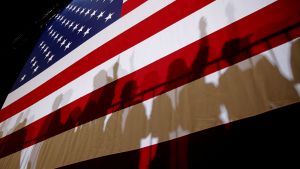 Shadows of people standing in front of an American flag