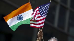 A man holds an American flag and an Indian flag during a parade