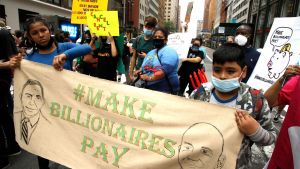 Children protesting and holding a sign that says "Make Billionaires Pay."