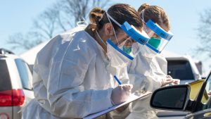 Doctors in PPE while at a COVID-19 testing site, holding clipboards